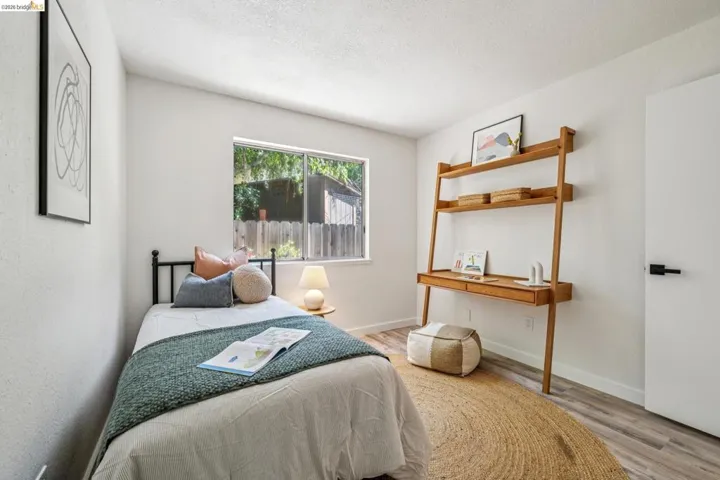 Bright room featuring wood-finish flooring, a window offering natural light, and a clean white door with a black handle