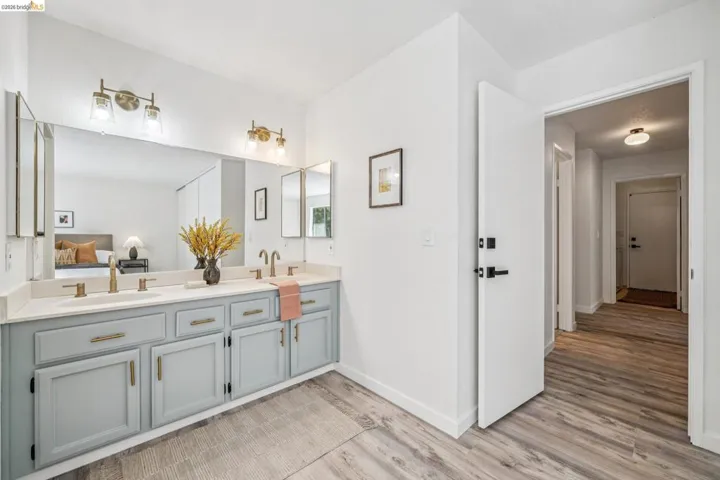 Bathroom vanity featuring a dual sink, light-toned countertop, and light blue cabinetry with brass hardware