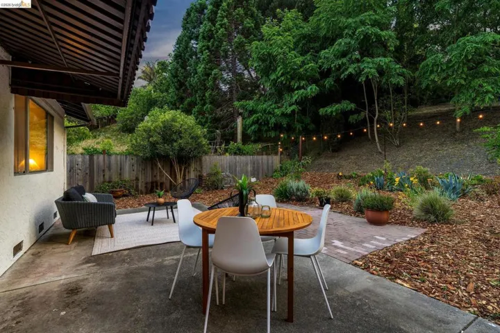 Expansive concrete patio offering a private outdoor living space, surrounded by a mature tree line
