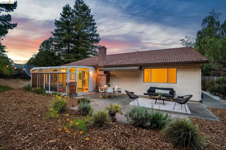 Expansive backyard featuring a curved glass sunroom, a tiled roof, and a stucco exterior