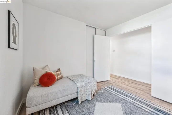 Room featuring light wood-finish flooring, white walls, and a recessed closet space with bi-fold doors