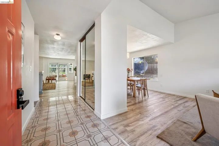 Entryway featuring patterned tile flooring, a vibrant orange entry door, and a mirrored closet