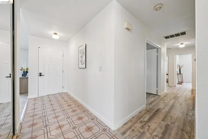 Entryway featuring patterned floor tile, a paneled door with black hardware, and an overhead flush mount light