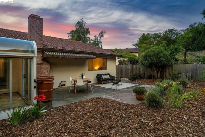 Expansive backyard featuring a brick chimney, a tiled roof, and a covered patio area with a retractable awning