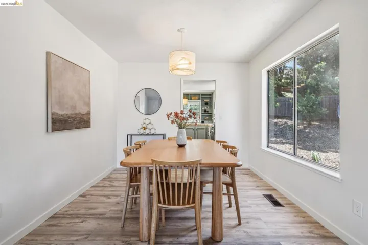 Dining area featuring wood-finish flooring, a contemporary pendant light fixture, and a large window offering exterior views