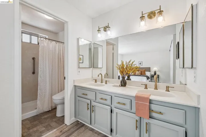 Double vanity with light gray cabinetry and brushed gold hardware, featuring a white countertop and dual undermount sinks