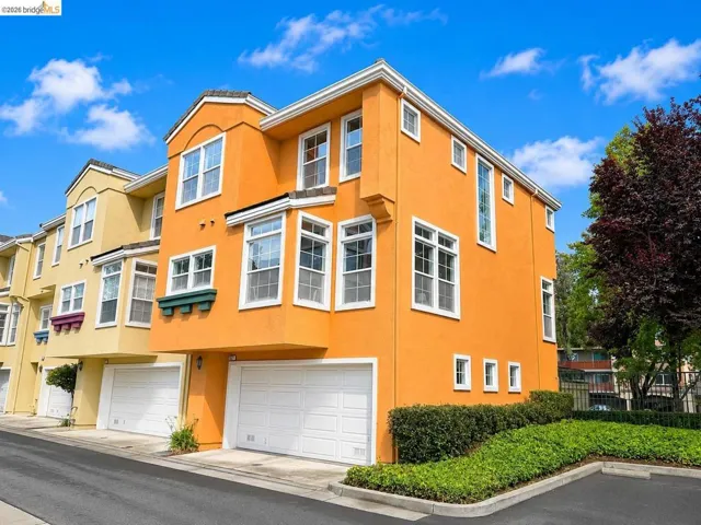 Three-story townhome with a bright orange stucco exterior and white trim