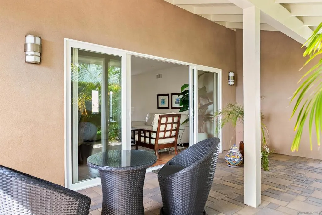 Covered patio area off the living area surrounded by lush landscaping