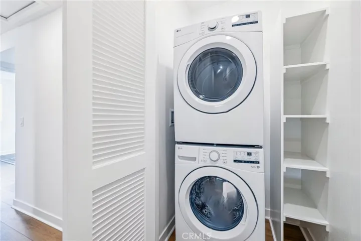 Model home laundry closet with built-in storage and space for stacked washer and electric dryer