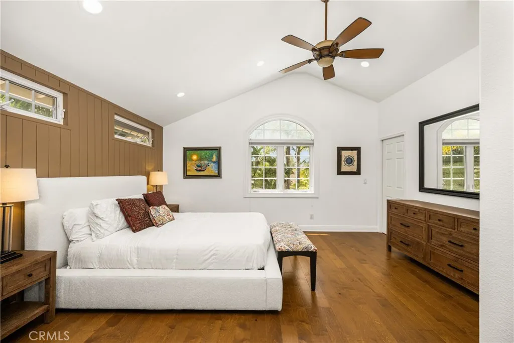 Master bedroom with high ceilings, ceiling fan....recessed lights and a window looking at lush greenary.