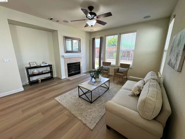 Living area featuring wood-finish flooring, a fireplace with a light-toned surround and mantel, recessed wall niche, and multiple windows