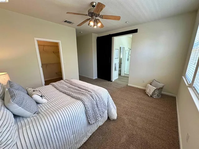 Bedroom with carpeted flooring, a ceiling fan with integrated lighting, and a window with blinds
