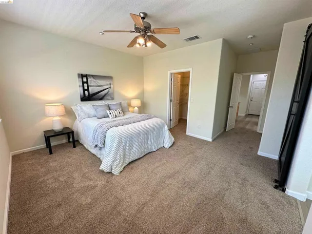 Spacious room featuring neutral carpeting, light-toned walls, and a ceiling fan with light fixture