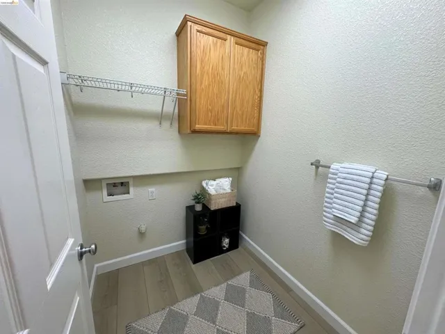 Laundry area featuring light wood-finish flooring, light-toned walls, and a built-in wire shelving unit