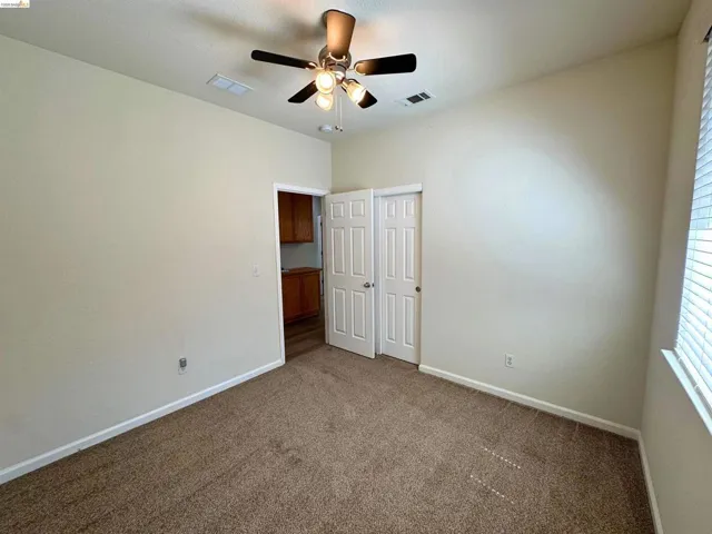 Carpeted room featuring a ceiling fan with integrated lighting, white baseboards, and a window with blinds