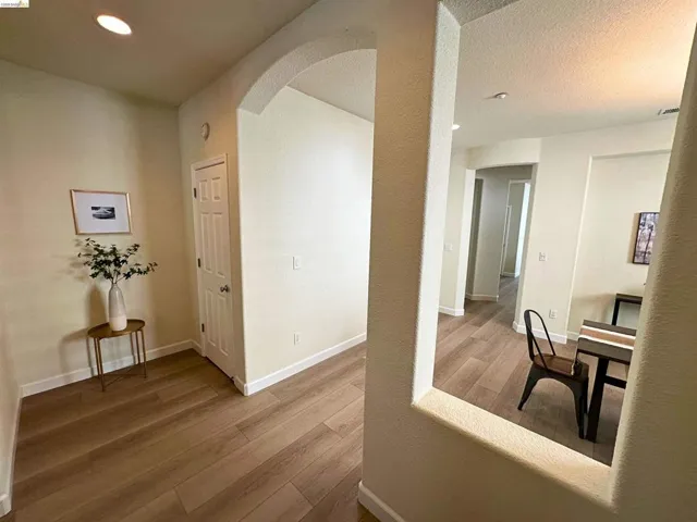 Spacious interior featuring wood-finish flooring, recessed ceiling lighting, arched doorways, and light-toned wall finishes