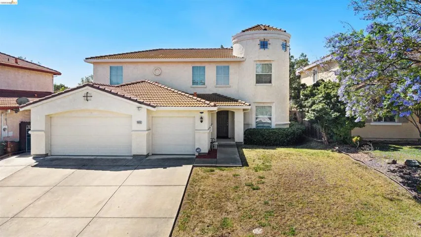 Stucco exterior with a tile roof, an arched entry, and a two-car garage
