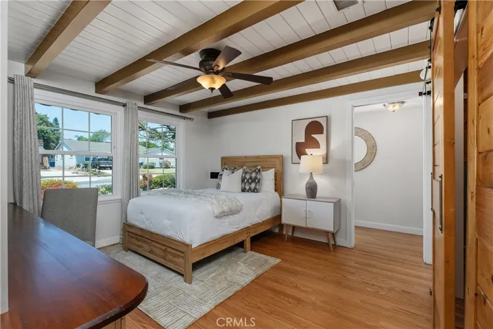 The third bedroom offers incredible flexibility, with refinished hardwood flooring, wood plank-and-beam ceiling detail, a ceiling fan, and a warm Craftsman-inspired feel.