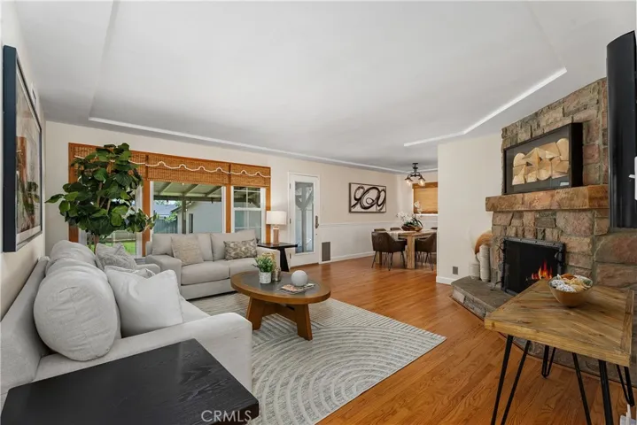 The living room opens with natural light, refinished hardwood flooring, bamboo window coverings, and views toward the backyard entertaining spaces.