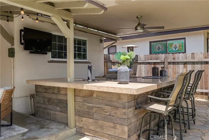 Designed for effortless entertaining, the covered outdoor bar includes pull-down shade, an outdoor weather-resistant television, generous counter space, and a layout made for gathering.
