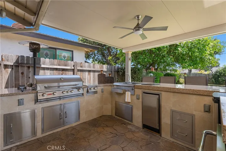 The custom-built outdoor kitchen features granite countertops, a top-of-the-line 42-inch Bull built-in gas grill, sink with ice box, dual-tap kegerator, refrigerator, separate ice maker, and covered bar seating.