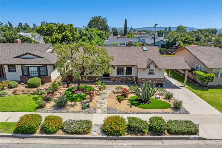 The front yard features drought-resistant landscaping, boulders, artwork, hardwired path lighting, and a welcoming front porch shaded by a Sunsetter awning.