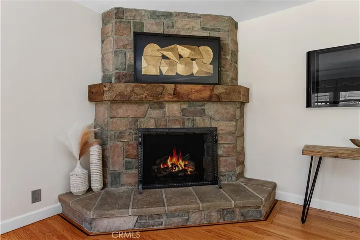 The custom gas fireplace showcases beautiful fieldstone rock craftsmanship, a raised hearth, and a handcrafted reclaimed barn wood mantel that adds warmth, texture, and character to the living room.