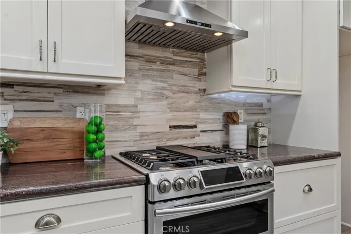 The Samsung smart 5-burner double oven gas range features Flex Duo cooking, built-in air fry, convection oven, Wi-Fi, and voice control, paired with a stainless hood and marble tile backsplash.