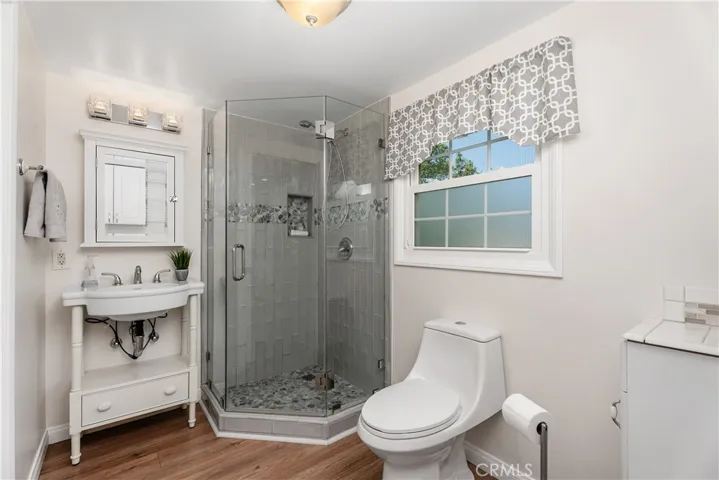 The expanded bathroom and laundry room was remodeled with a modern walk-in shower, updated sink, new toilet, and built-in cabinetry for added storage and everyday function.
