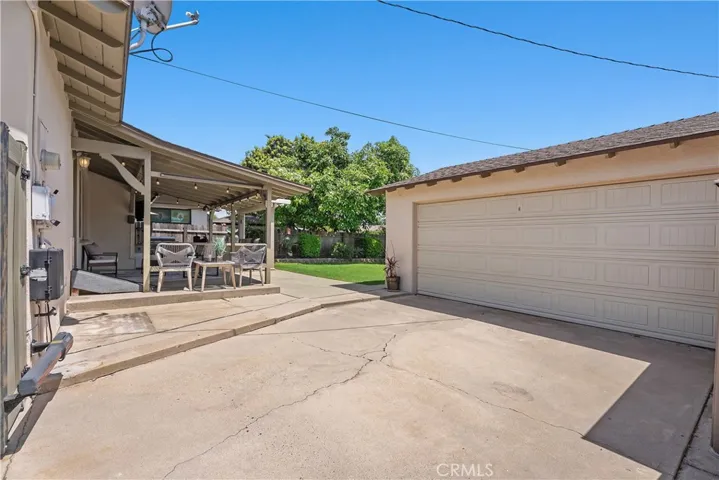 The long driveway extends through the porte cochere to the detached two-car garage, offering additional parking, flexible outdoor space, and remote-controlled gated access to the backyard.