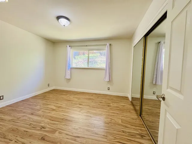 Room featuring wood-finish flooring, a window with exterior visibility, and a ceiling-mounted light fixture