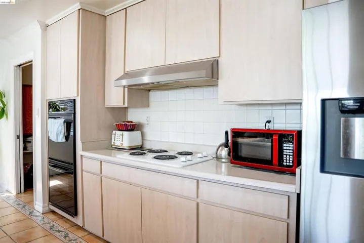 Kitchen featuring light wood-finish cabinetry, a built-in double oven, and a stainless steel refrigerator