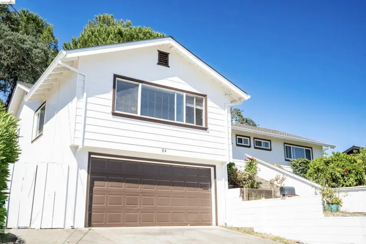 White exterior with brown trim details, featuring a two-car garage and upper-level window