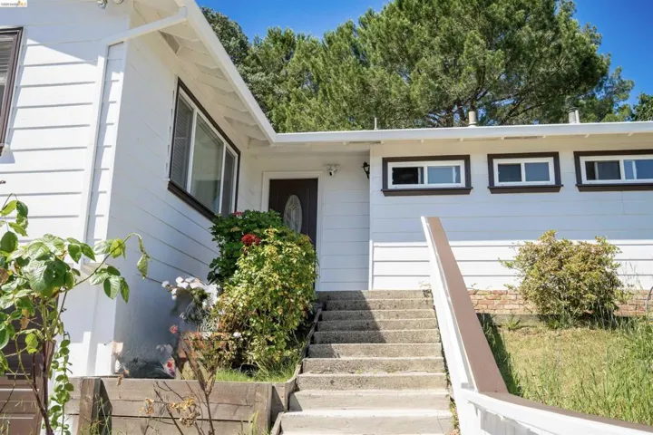 White exterior siding with dark trim windows and a dark entry door featuring an oval glass insert
