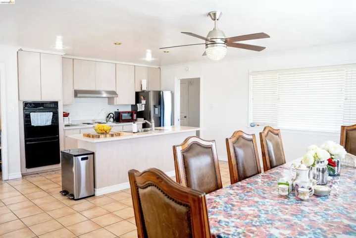 Spacious kitchen featuring light-toned cabinetry, stainless steel appliances, a center island with sink, and tile flooring