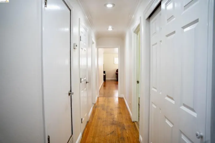 Hallway featuring wood-finish flooring, recessed lighting, and crown molding