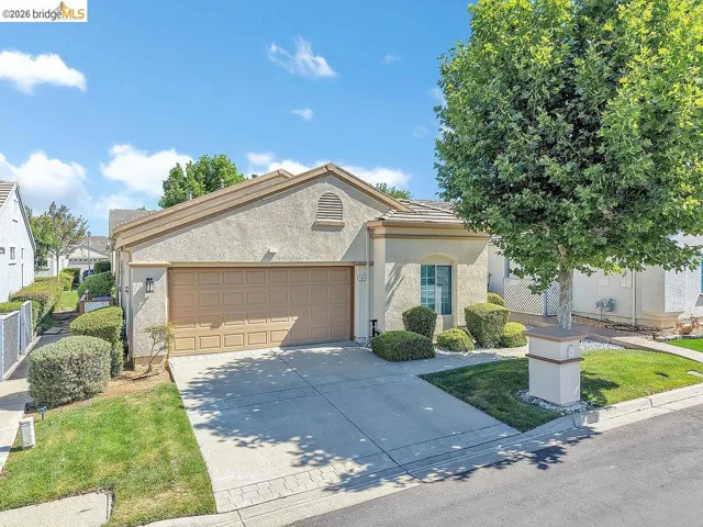 Stucco exterior residence featuring an attached two-car garage, concrete driveway, and a tile roof