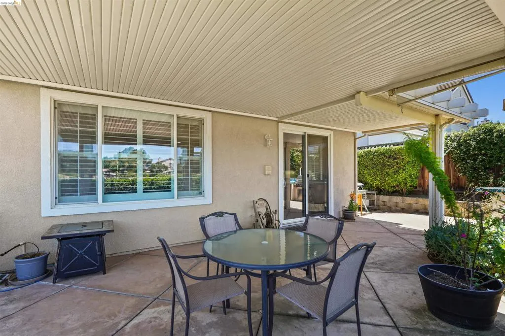 Covered patio area featuring a concrete slab, sliding glass door entry, and an overhead patio cover