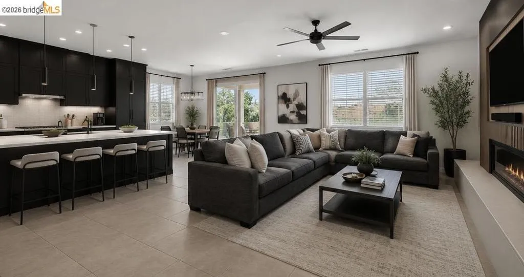 Open-concept living space featuring a modern kitchen with dark cabinetry, a white countertop island with seating, and a dining area