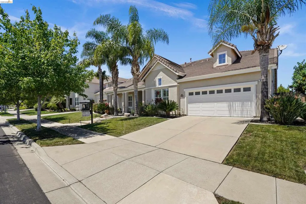 Contemporary stucco exterior with a two-car garage, dormer window, and tile roof