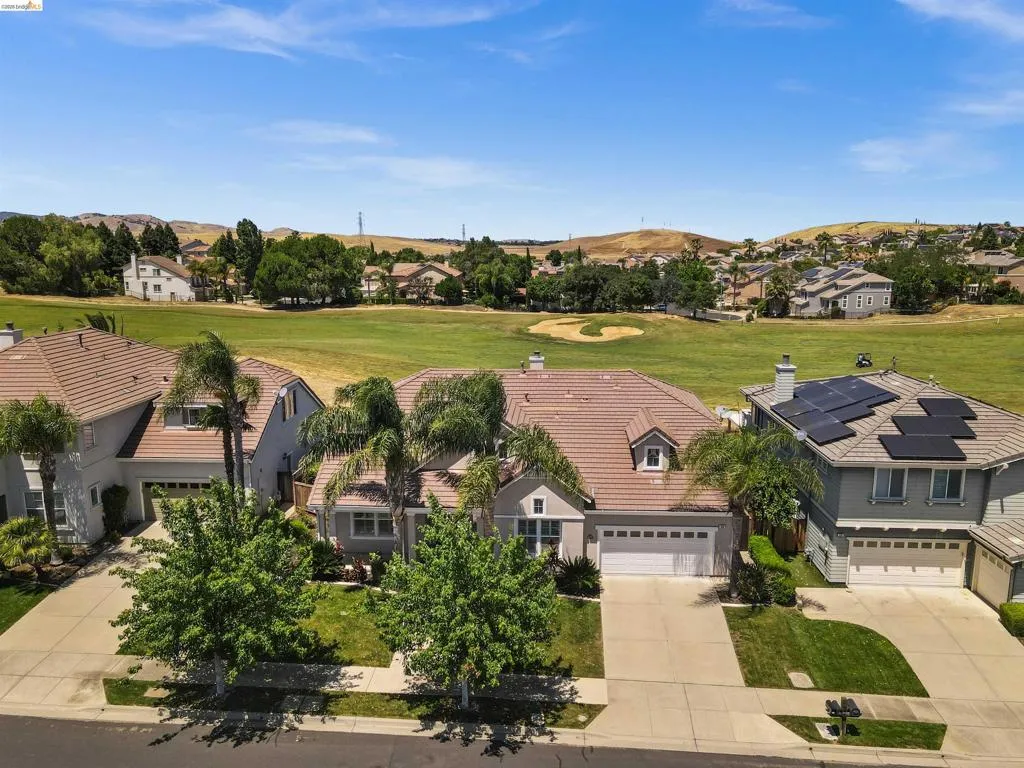 Residence with a two-car garage, mature front yard trees, and a terracotta-style roof