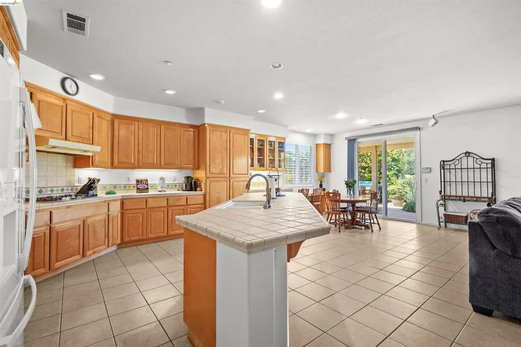 Spacious kitchen featuring warm wood cabinetry and a tiled center island with sink