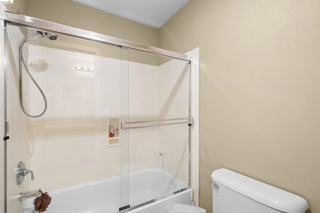 Bathtub and shower combination featuring a glass sliding door enclosure, chrome fixtures, and a built-in shower niche