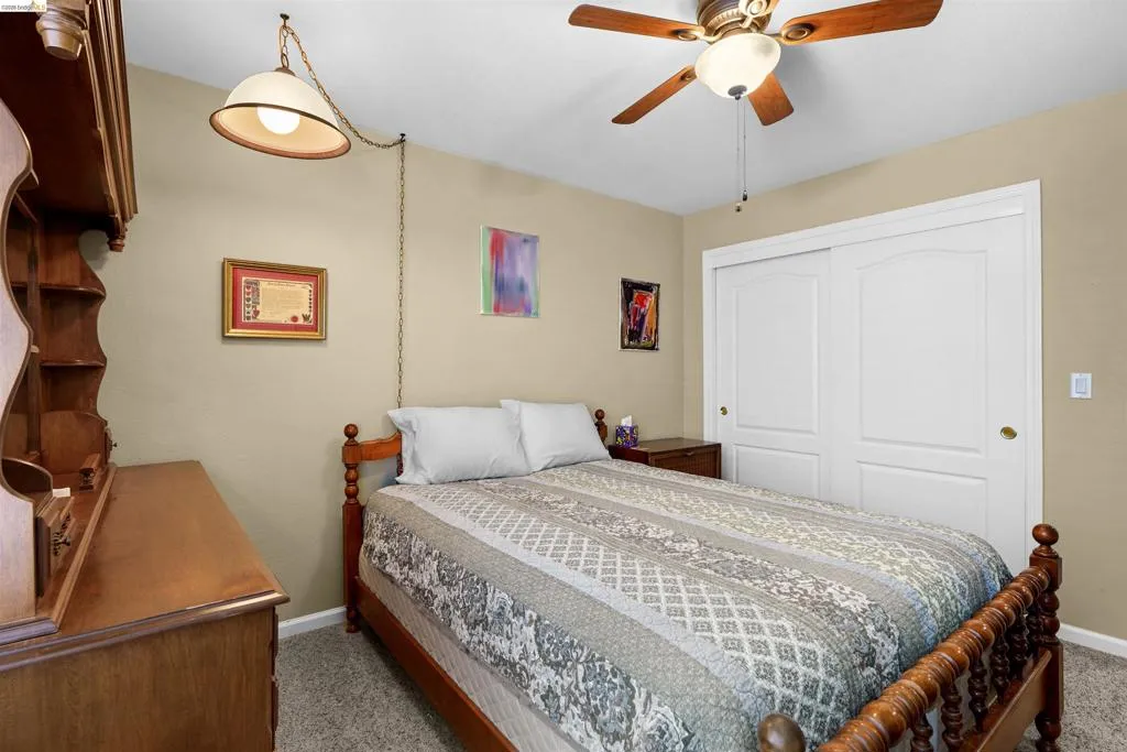 Carpeted room featuring a ceiling fan with integrated lighting, neutral wall paint, and white sliding closet doors