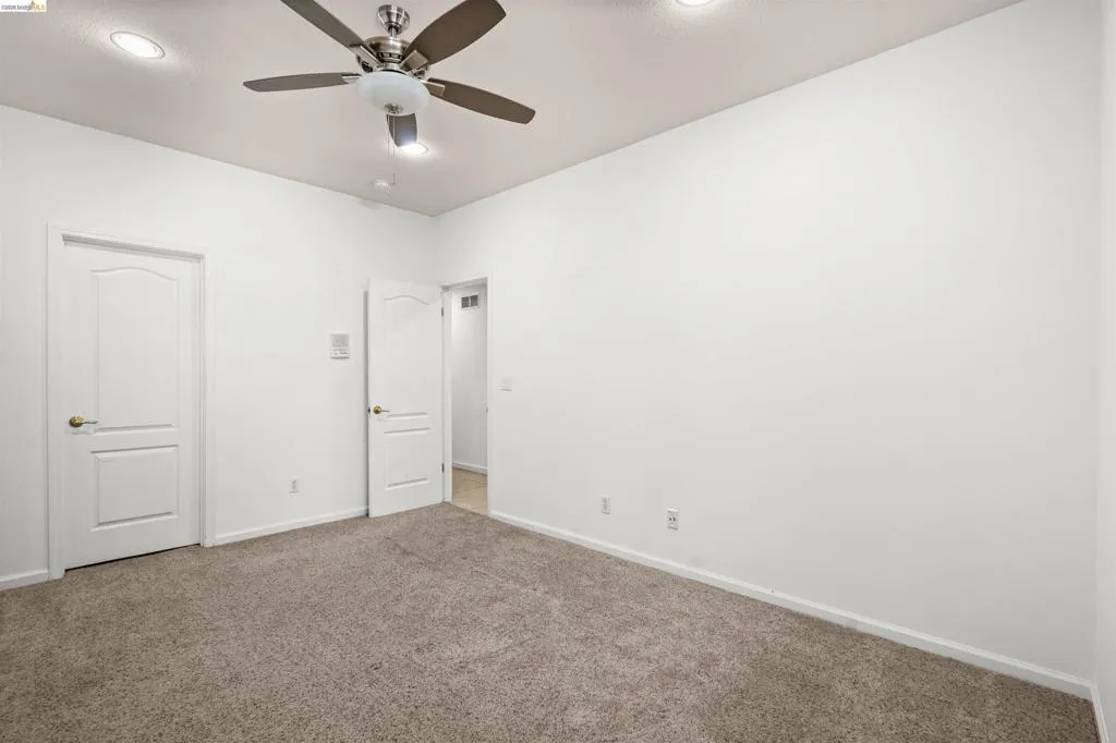 Carpeted interior space featuring white walls and a ceiling fan with integrated lighting