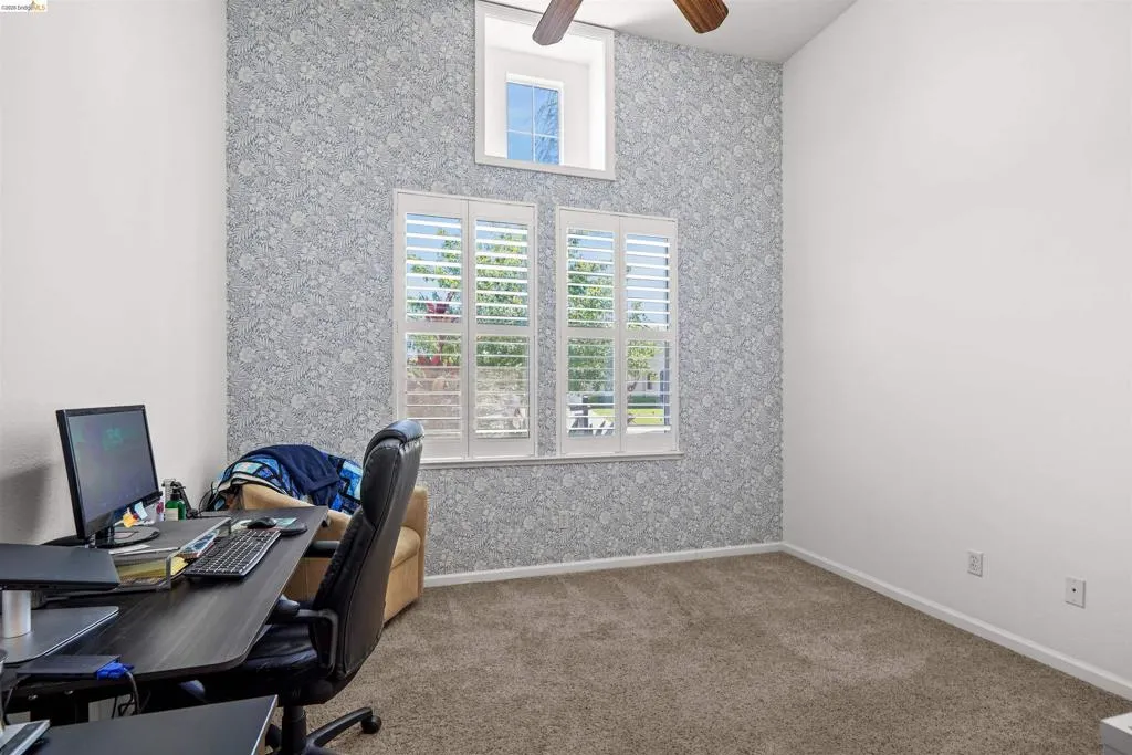Room featuring vaulted ceilings, a decorative accent wall, and carpet flooring
