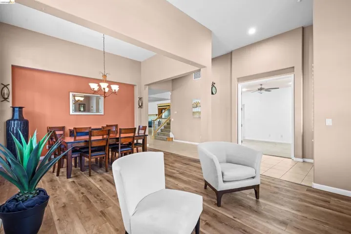 Dining area with wood-finish flooring, a decorative chandelier, and a contrasting accent wall