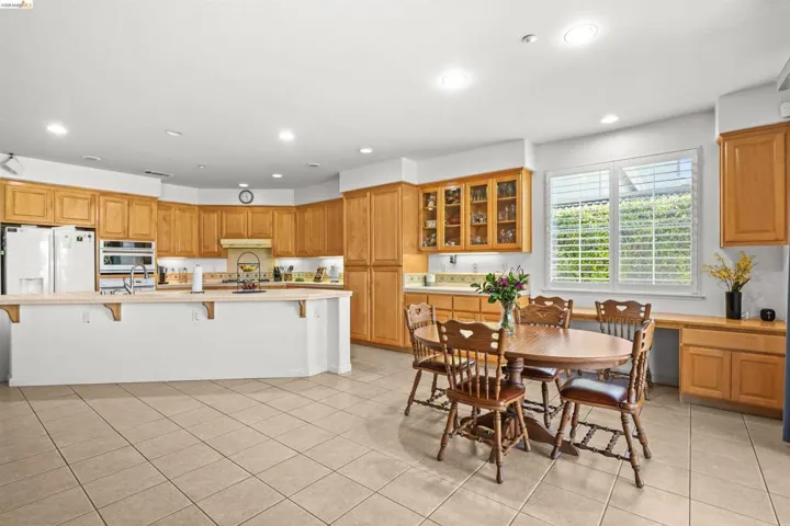 Spacious kitchen featuring extensive wood cabinetry, tile flooring, a breakfast bar, recessed lighting, and a built-in desk area