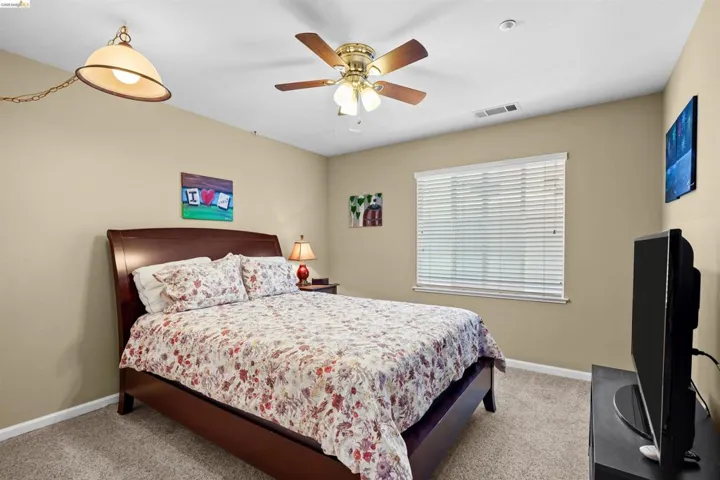 Bedroom featuring neutral wall colors, carpet flooring, a window with blinds, and a ceiling fan with integrated lighting
