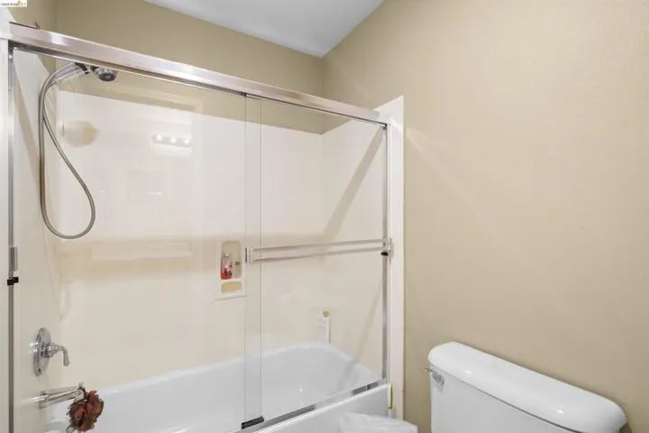 Bathtub and shower combination featuring a glass sliding door enclosure, chrome fixtures, and a built-in shower niche